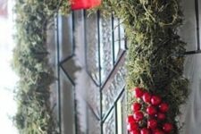 a frame Christmas wreath covered with moss, berries, a large red bow and a red ribbon on top is amazing