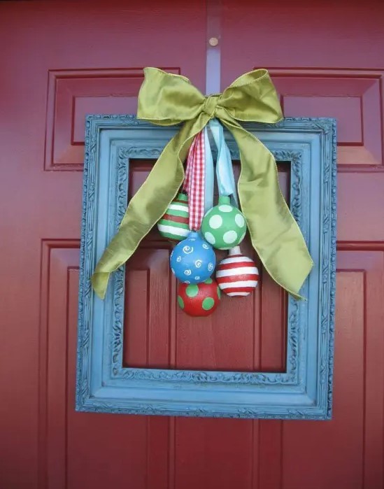 a front door Christmas wreath made of a blue frame with colorful ornaments and a green silk bow is a whimsy and cool idea
