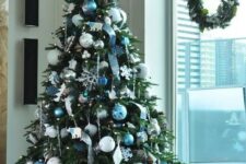 a frozen Christmas tree decorated with blue and silver ornaments, ribbons, snowflakes and other plywood ornaments is a chic and cool idea