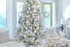 a glam Christmas tree decorated with white, silver, blue and pastel blue ornaments, ribbons and fabric poinsettias