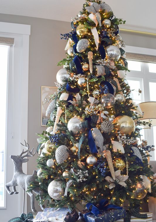 a glam Christmas tree with lights, oversized silver and gold ornaments, navy, gold and striped ribbons and navy berry decor