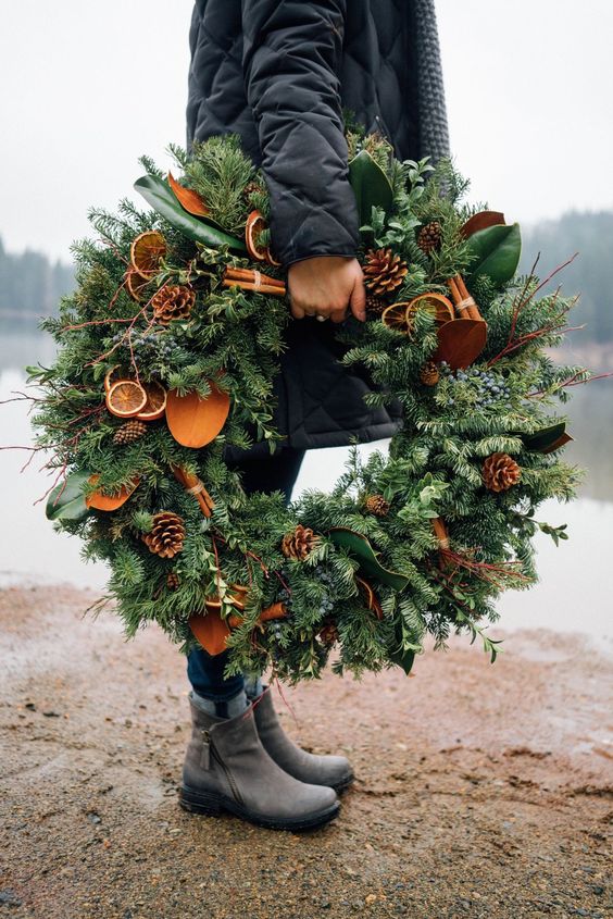 a gorgeous natural meets rustic Christmas wreath of evergreens, pinecones, twigs, citrus slices and magnolia leaves