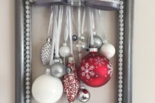 a grey frame Christmas wreath with white, silver and red ornaments and a large silver bow on top