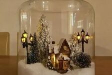 a jar with faux snow, a mini house, some bottle brush Christmas trees and street lights is an amazing Christmassy terrarium