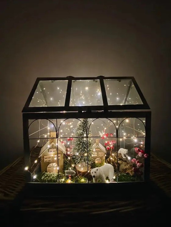 a large Christmas terrarium with moss, lights, mini houses, some polar bears and berries plus a bottle brush Christmas tree