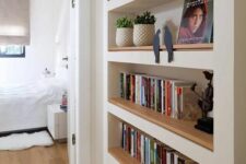 a large niche with built-in shelves accented with light-stained wood, with books, decor and potted plants is awesome
