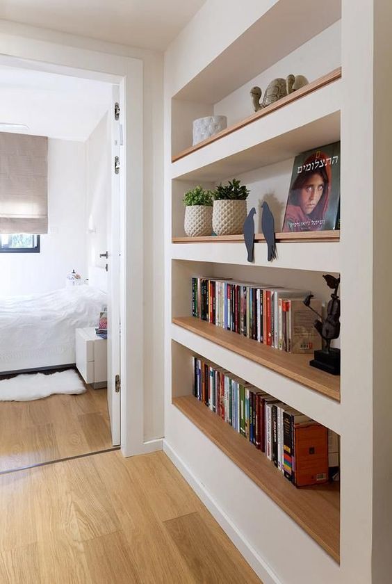 a large niche with built-in shelves accented with light-stained wood, with books, decor and potted plants is awesome