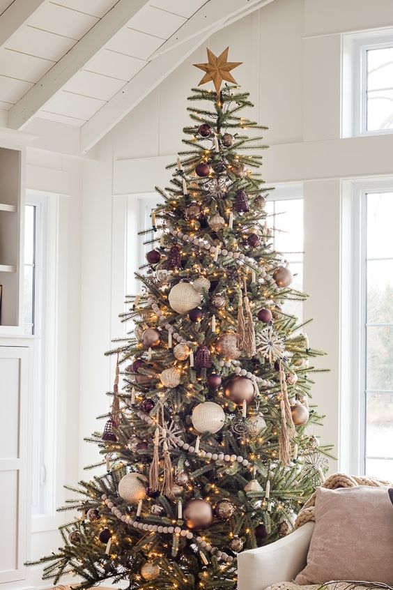 a lovely rustic Christmas tree with white, bronze, gold and silver ornaments, snowflakes, tassels, lights and bells
