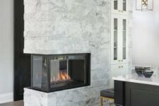 a marble double-sided fireplace to illuminate and warm up the kitchen and the entryway is a cool idea to add coziness