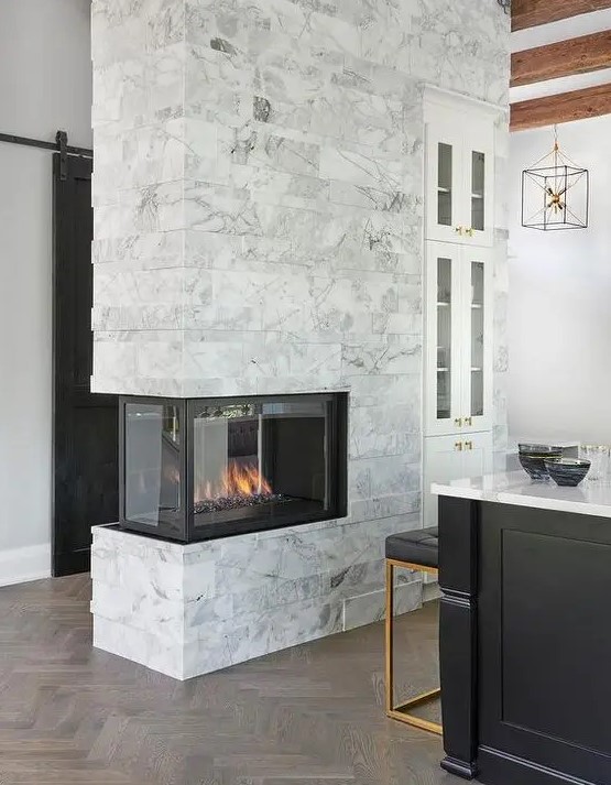 a marble double sided fireplace to illuminate and warm up the kitchen and the entryway is a cool idea to add coziness