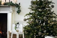 a modern Christmas tree decorated with black sequin, gold and silver half moon ornaments plus a neutral basket tree skirt