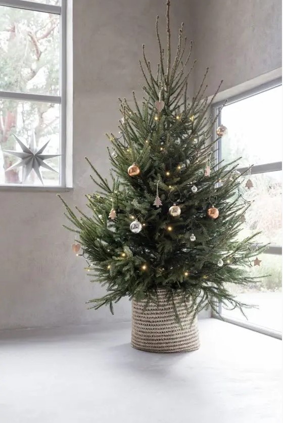 a modern Christmas tree with silver, copper and gold ornaments and lights plus a woven basket is a gorgeous idea to rock