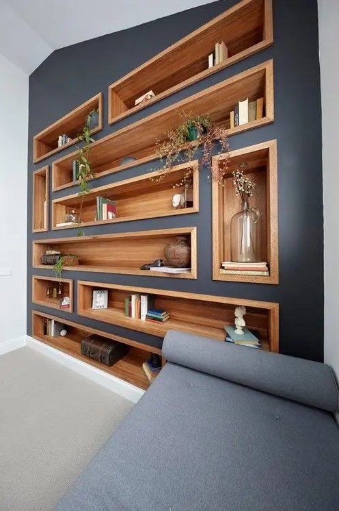 a modern living room with a graphite grey accent wall dotted with stained wood niche shelves used as a large display