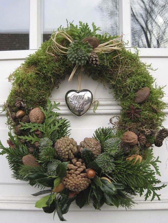 a natural Christmas wreath of moss, greenery, foliage, nuts, acorns, pinecones and a silver heart