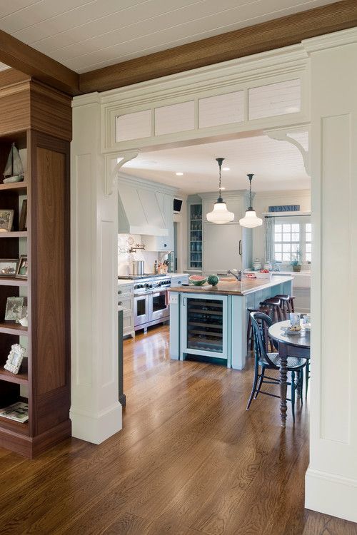 a neutral and pastel kitchen with a dining zone and a transom window installed in the doorway shows off vintage chic
