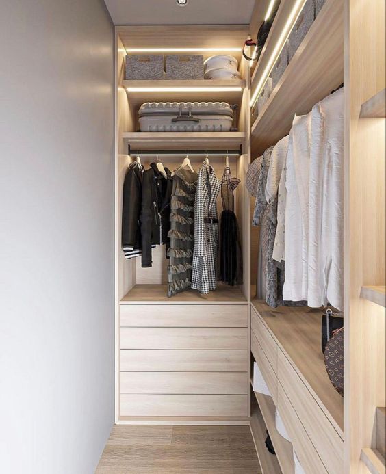 a neutral narrow closet with open storage lit up shelves, clothes hanging, drawers and shelves is a lovely space with great organization