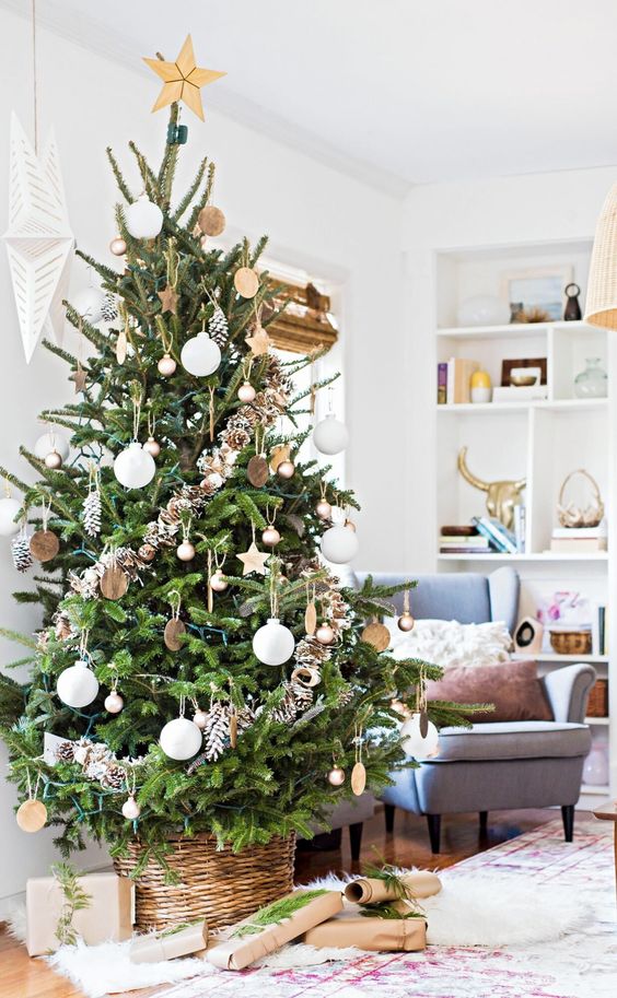 a pretty Christmas tree with white and copper ornaments, snowy pinecones and lights plus a basket for a cozy rustic feel