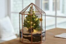 a pretty and cool Christmas terrarium with some faux snow, a Christmas tree with lights, a billy ball and a pinecone