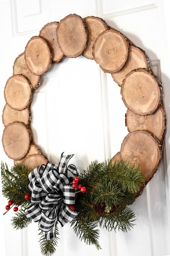 a pretty and cozy rustic Christmas wreath of tree slices, evergreens, berries, a buffalo check bow is a cool decoration