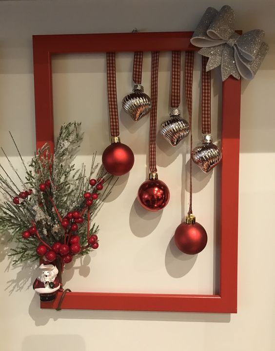 a red frame Christmas wreath with silver and red ornaments, a silver glitter bow, evergreens, berries and a Santa Claus