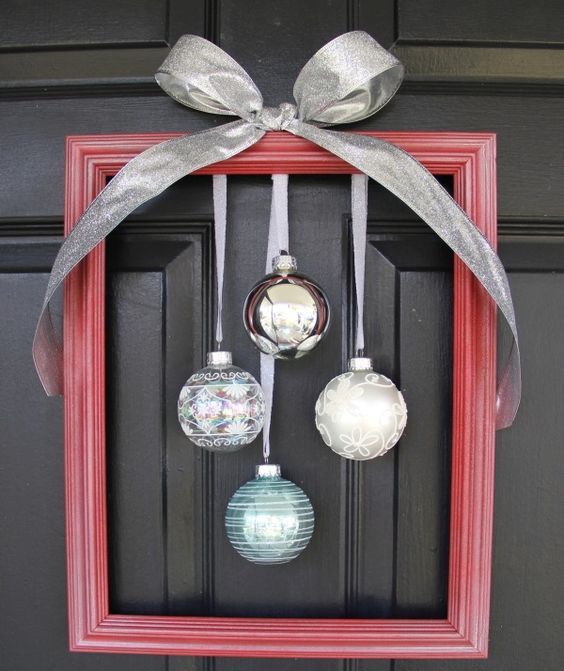 a red frame Christmas wreath with silver, white and blue ornaments and a large bow on top is a gorgeous idea