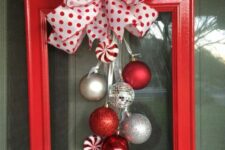 a red picture frame with silver, disco ball and candy Christmas ornaments and a polka dot bow on top is a lovely decor idea for the holidays