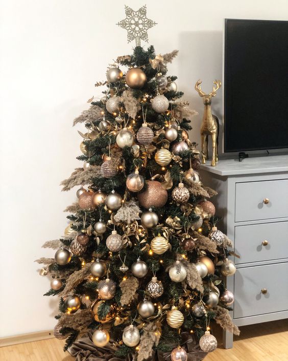 a refined Christmas tree decorated with gold, silver, copper Christmas ornaments, pampas grass and a star topper