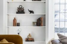 a refined living room with a large niche in the wall featuring some shelves, books and decor is a gorgeous space