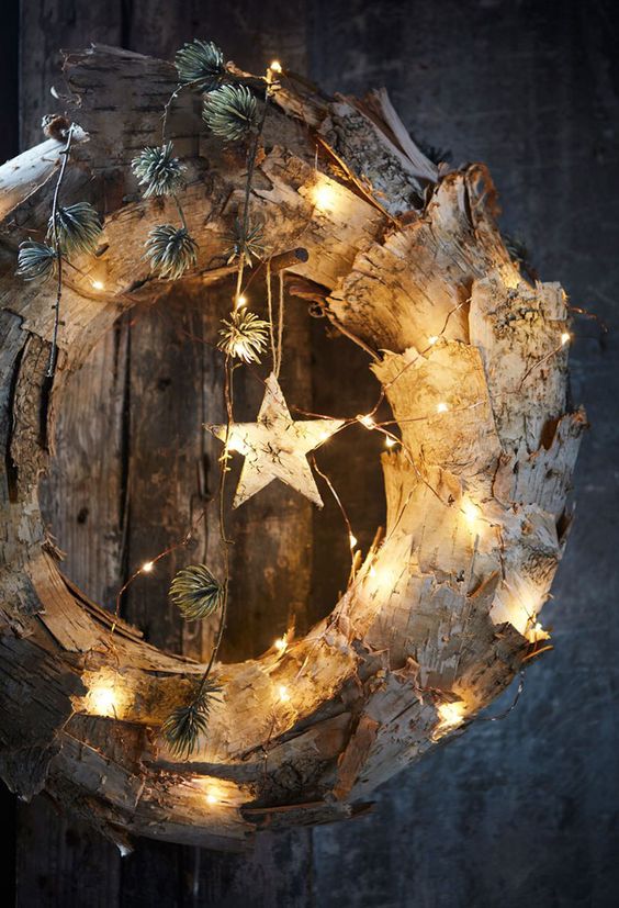 a rustic Christmas wreath of bark, lights, bark stars and greenery is a cool and unusual decor solution