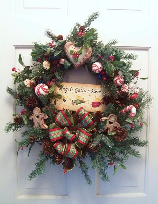 a rustic Christmas wreath of evergreens, greenery and pinecones plsu whisy red Christmas ornaments