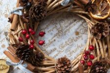 a rustic Christmas wreath of vine, pinecones, berries, cinnamon sticks, red stars and citrus slices is cozy and lovely
