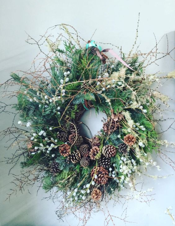 a rustic Christmas wreath with twigs, blooming branches, berries and pinecones is an amazing decoration for a woodland or rustic space