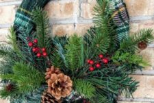 a rustic Christmas wreath wrapped with a green plaid scarf, evergreens, pinecones, berries is a very easy and cool DIY
