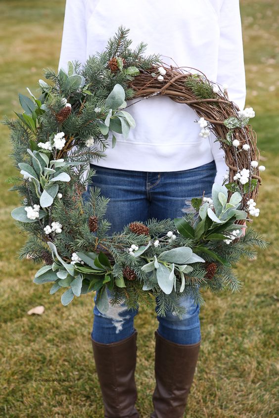 a rustic farmhouse Christmas wreath with evergreens, pinecones and foliage plus white berries is a cool decor idea