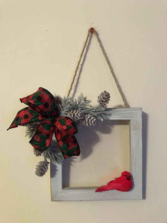 a rustic frame Christmas wreath with a red faux bird, a plaid bow, bleached pinecones and evergreens is all cool