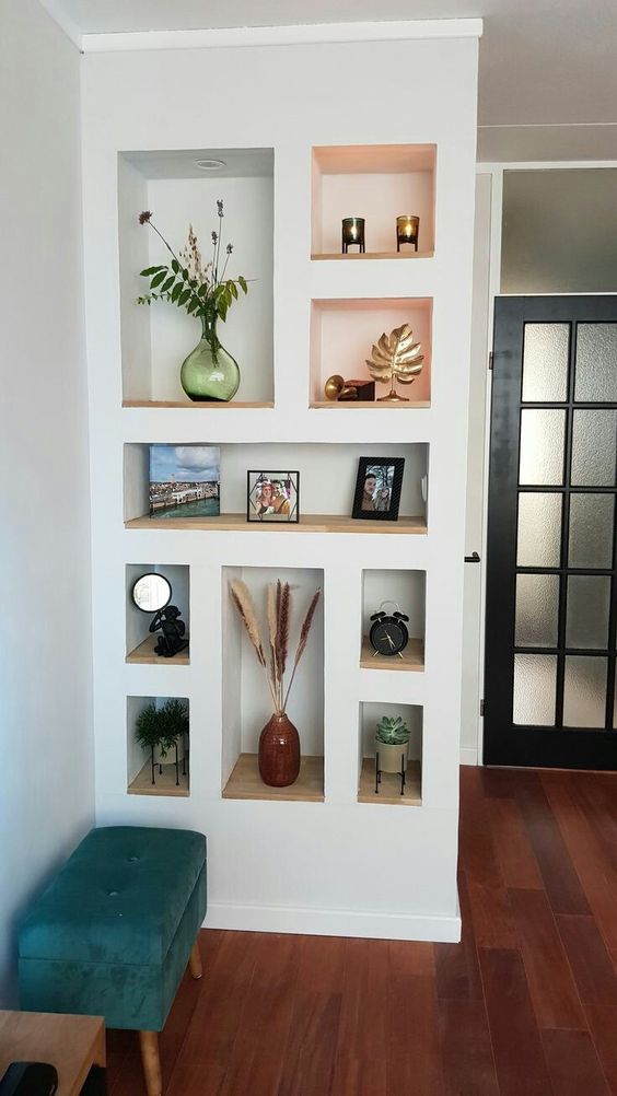 a series of niche shelves with potted plants, candleholders and photos that add color and interest to the space