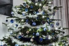 a shining Christmas tree with lights, blue, navy and silver ornaments and stars is a beautiful and chic idea