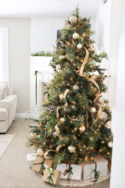 a shiny and cool Christmas tree with metallic ornaments, gold ribbons, pinecones and branches plus lights
