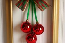 a simple and classy Christmas wreath of a gold frame, red ornaments and a green, red and gold bow on top can be easily DIYed