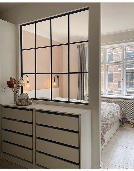 a small and cozy bedroom featuring an interior window that brings some natural light and makes the walk-in closet cozier