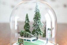 a small and cute Christmas terrarium with a green car carrying a tree and some mini trees and snow is cool