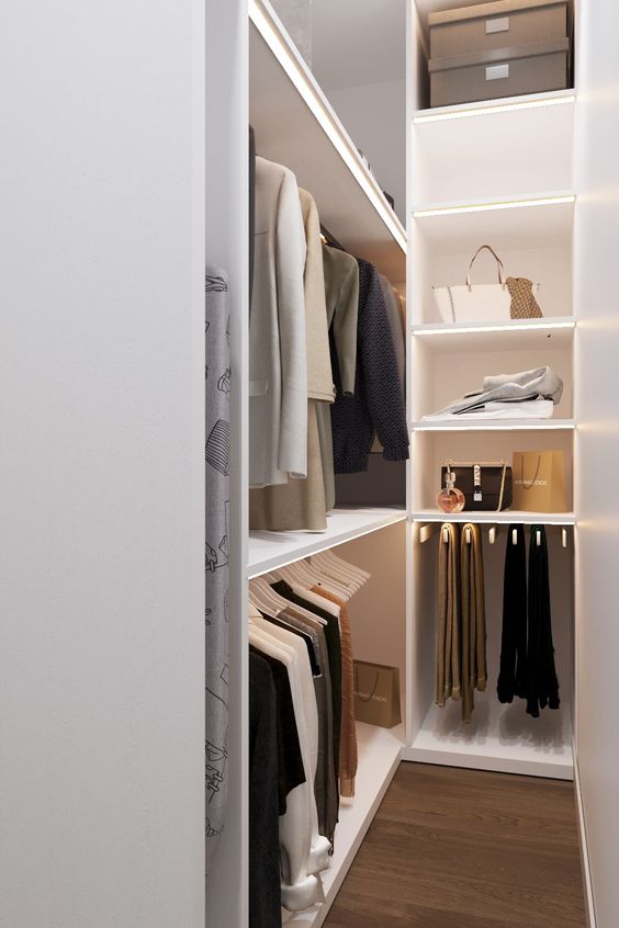 a small and narrow minimalist closet with open storage units, lit up shelves and some boxes on top doesn't look cluttered and is well-organized