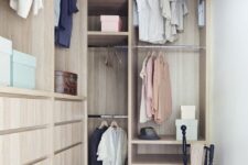 a small and narrow yet well-organized closet with light-stained furniture with open storage, drawers and shelves plus a black chair