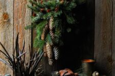 a small rustic Christmas wreath with evergreens, pinecones and a single candle is a pretty decoration to rock