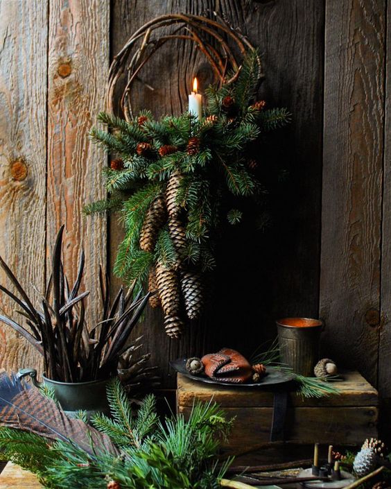 a small rustic Christmas wreath with evergreens, pinecones and a single candle is a pretty decoration to rock