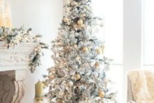 a snowy Christmas tree with gold and silver ornaments and a snowflake on top looks glam