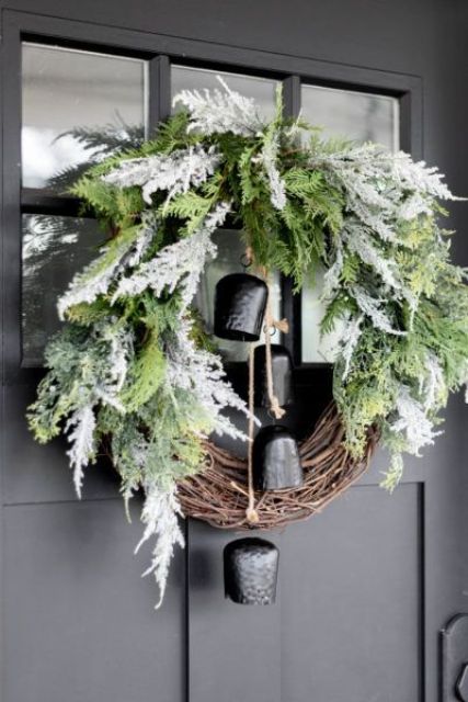 a stylish Christmas wreath of vine, greenery and pale greenery and large black bells is a chic and lovely decoration