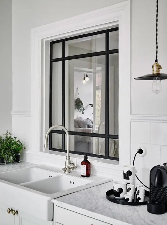 a stylish black frame window from the kitchen to the entryway is a cool idea to fill the entryway with natural light