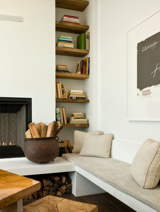 a tall and narrow niche with dark-stained shelves and books on them is a cozy addition to the fireplace nook