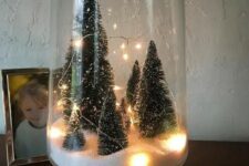 a tall glass terrarium with faux snow, some bottle brush trees and lights is easy to make yourself and looks cool